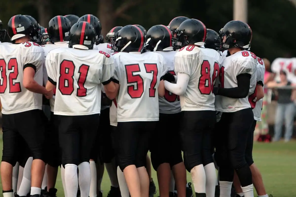 How tight should a football helmet be? This football team huddled together in the middle of the playing field is discussing helmet comfort.