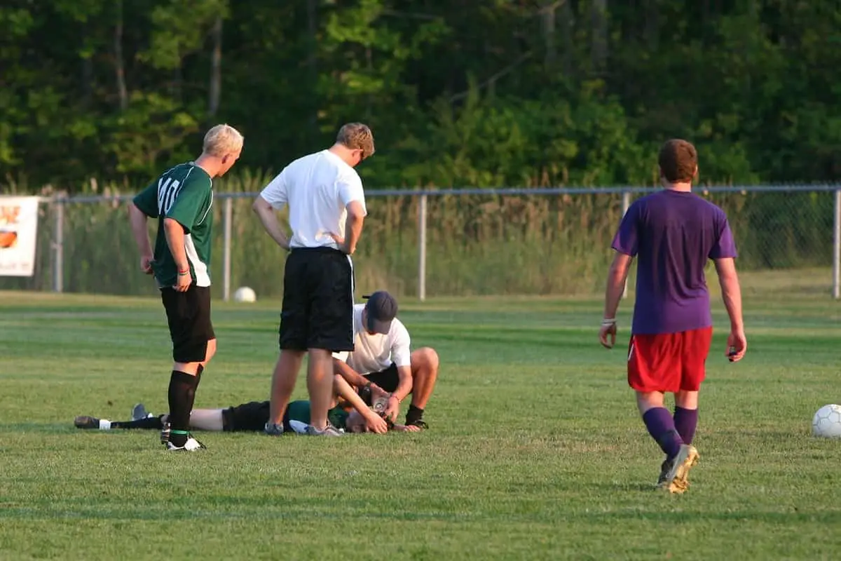 Can Helmets Prevent Concussions? 1 injured soccer player on the ground being attended to by the team doctor