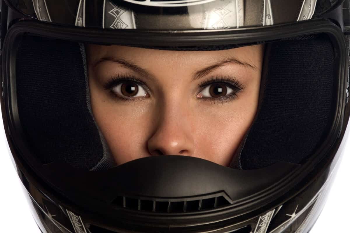 close up of attractive woman wearing a motorcycle helmet looking out through the front of the helmet