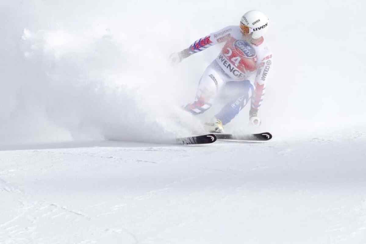 downhill skier wearing a Uvex helmet in a mist of fine powder snow