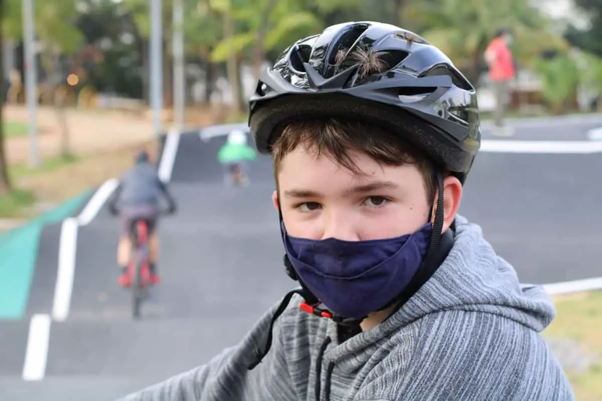 A boy looking like he doesn't really want to wear his bike helmet