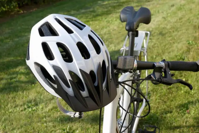 white bike helmet sitting on handle bar of whit bicycle