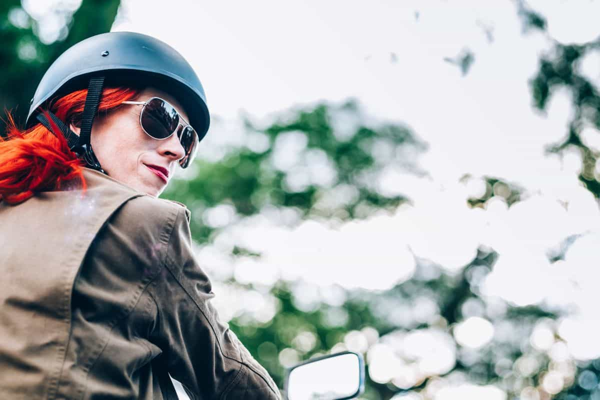 Woman with red hair wearing a black half helmet looking to her right.