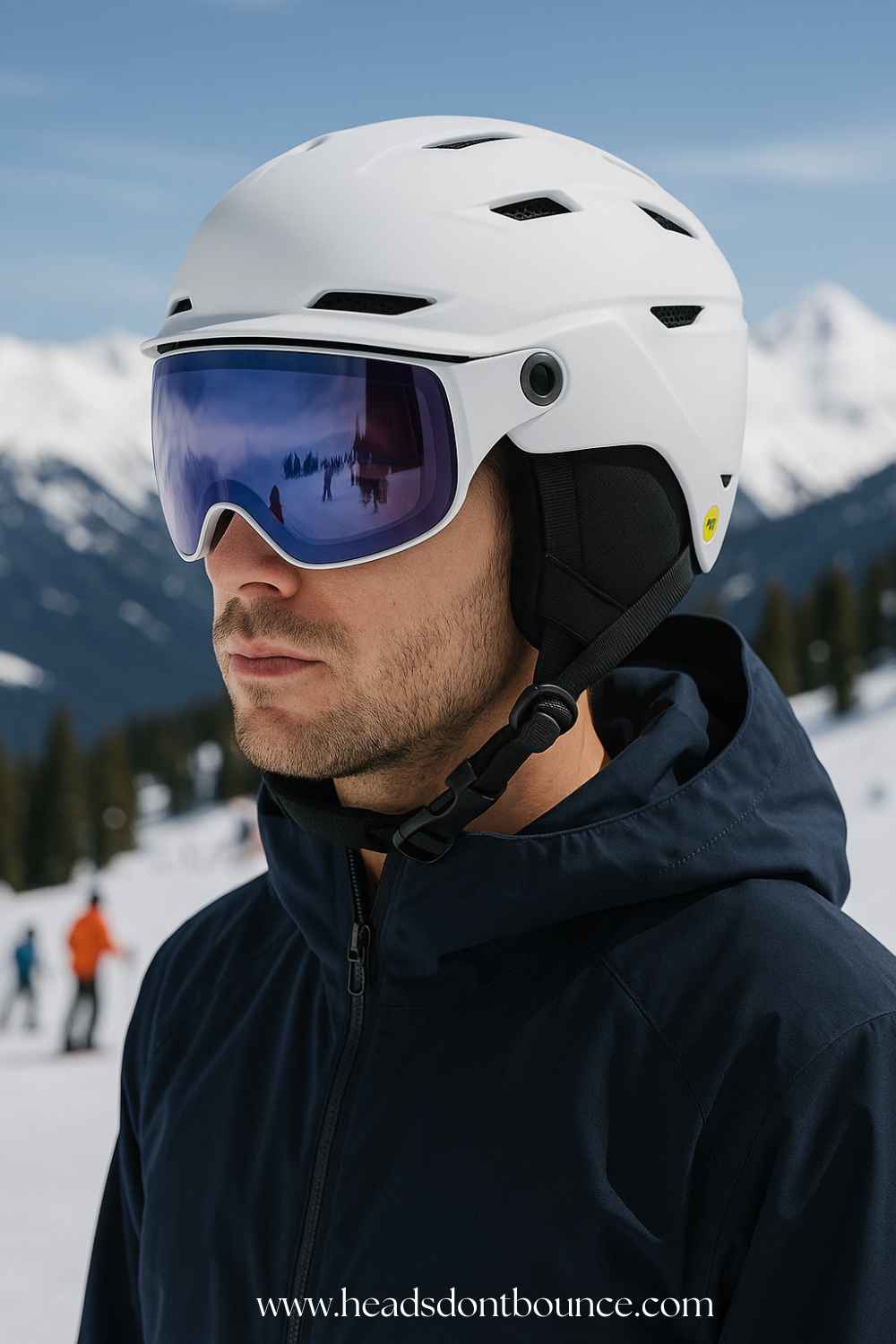 Candid close-up of a man wearing a white ski helmet with visor, standing on a snowy slope with mountains and trees in clear focus behind him.