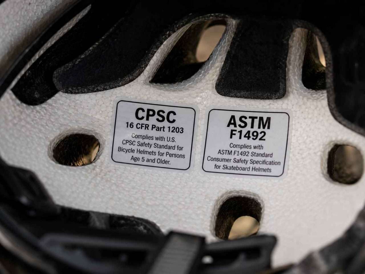 Close-up of CPSC 16 CFR Part 1203 and ASTM F1492 certification stickers inside a dual-certified helmet.
